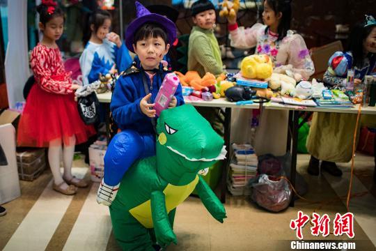 騎著可愛”小恐龍“的孩子參加愛心義賣。 泱波 攝